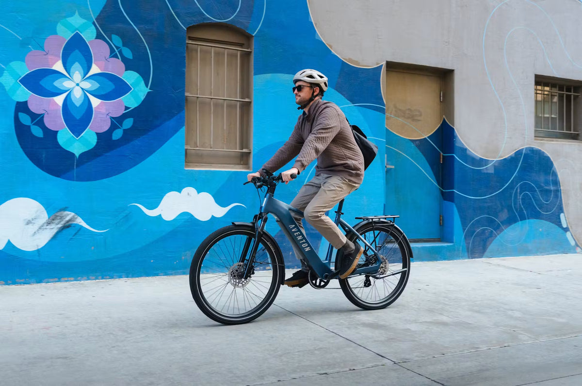 Man riding a bicycle in front of a colorful mural on a building.
