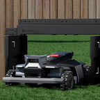 Robotic lawn mower in a grassy area with a wooden fence in the background