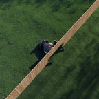 Robotic lawn mower on a green lawn with a wooden deck.